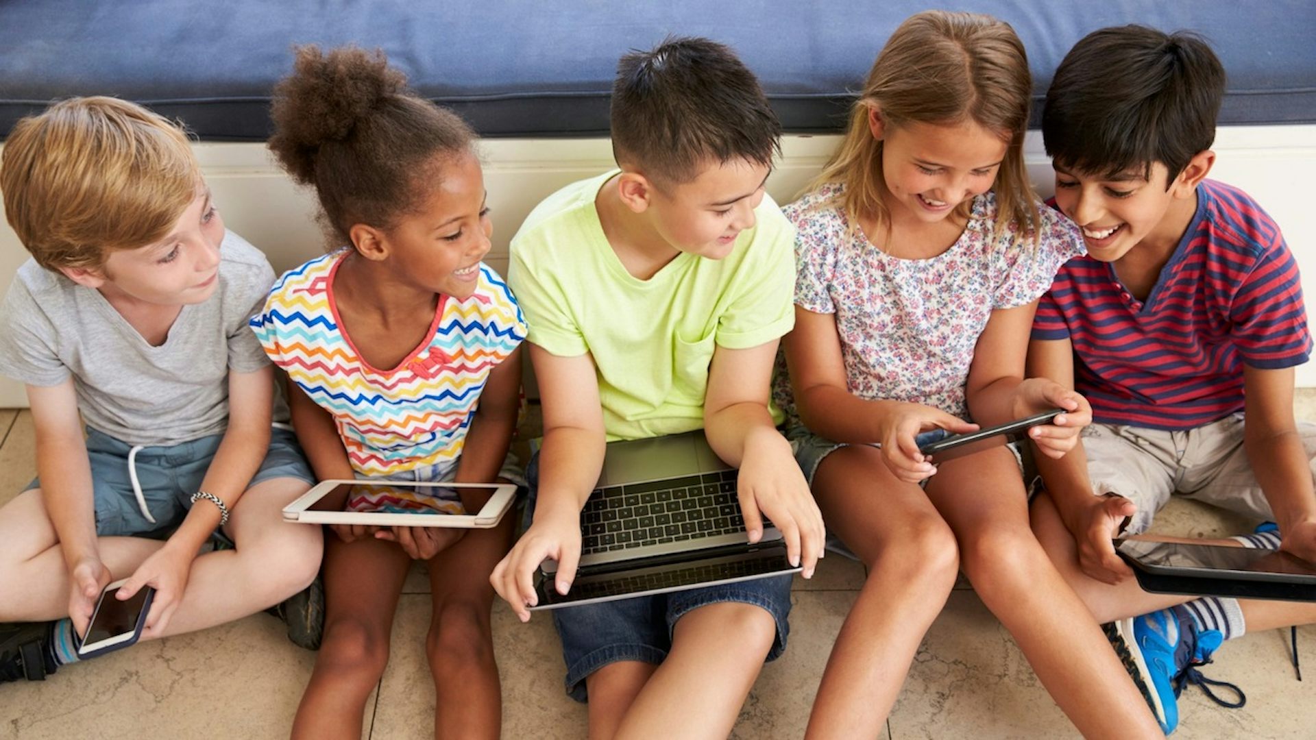 Five children using digital devices