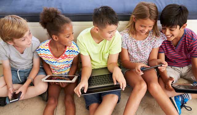 Five children using digital devices
