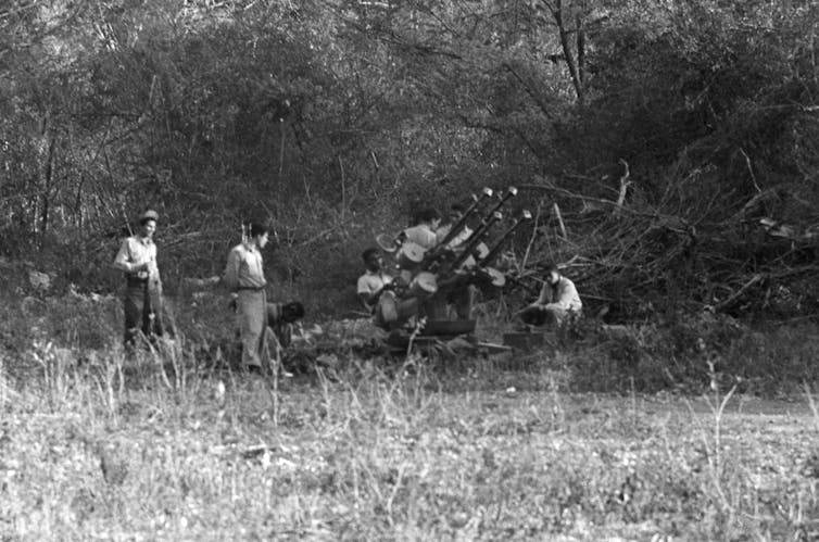 Black-and-white image of militiamen with weapons in a field