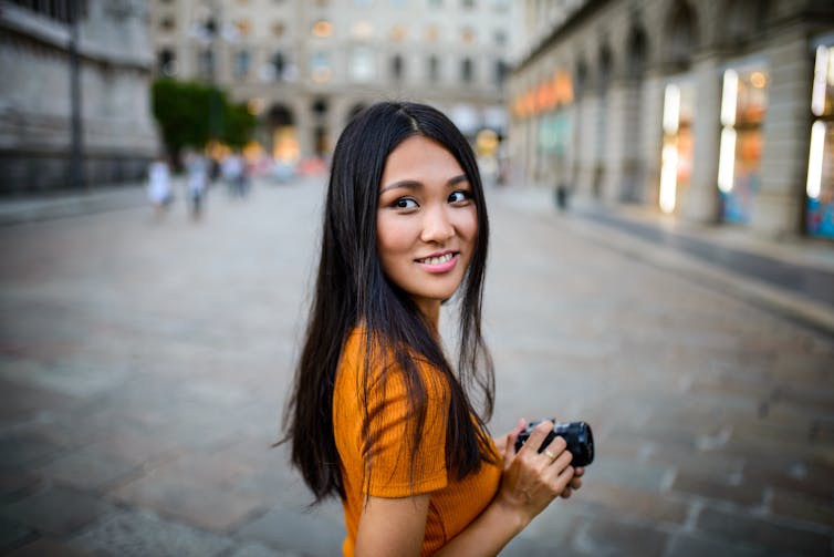 Young Asian American Woman holding a cellphone.