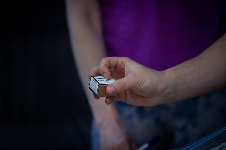 Person holding small container of heroin