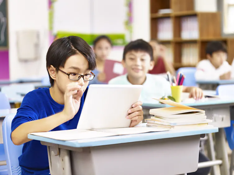 Children sit behind desks in a classroom