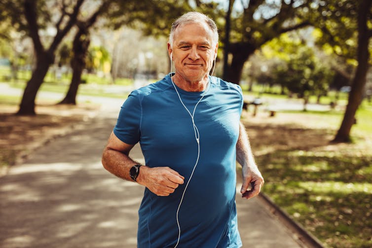 A man wearing headphones jogs in the park.