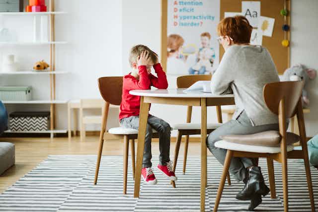 Un enfant et un professeur assis à un table.