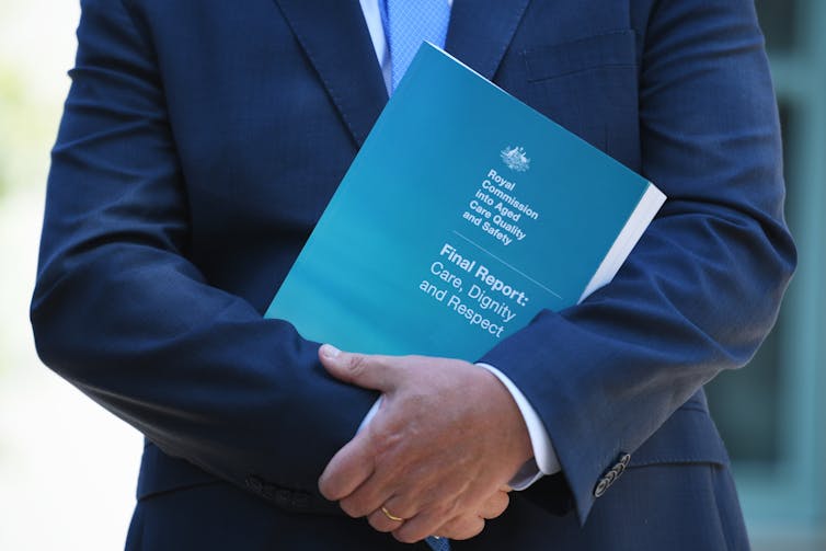 Prime Minister Scott Morrison holding a copy of the aged care royal commission report.