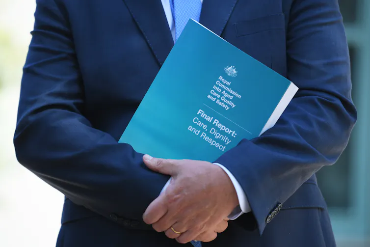 Prime Minister Scott Morrison holding a copy of the aged care royal commission report.