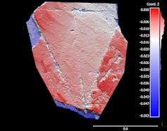 A scale bar in blue and red is visible to the right of a smooth piece of stone, also in blue and red, that features a triangular shape.