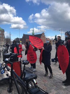 Protesters gather in a square with red banners