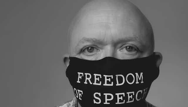 A bald man wearing a COVID mask with the words 'Freedom of Speech'.