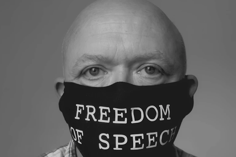 A bald man wearing a COVID mask with the words 'Freedom of Speech'.