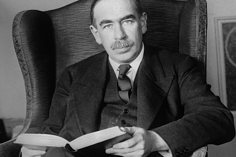 John Maynard Keynes reading a book on an armchair