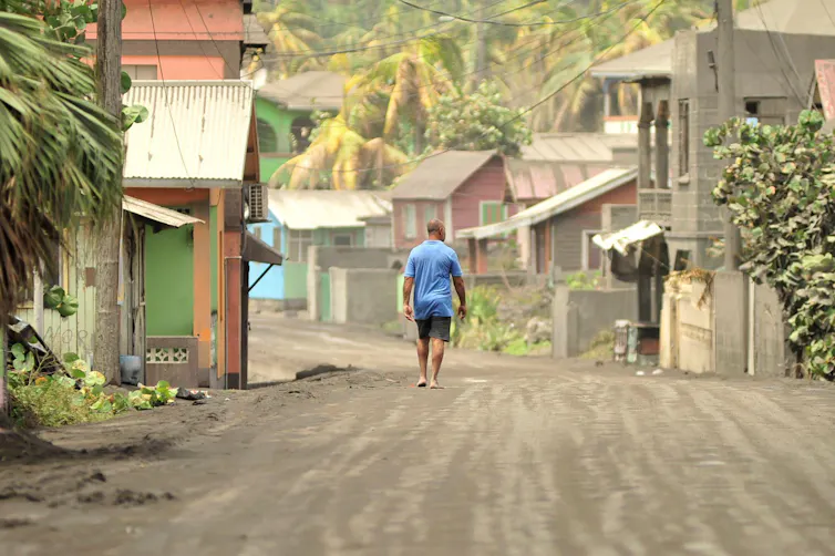 A man walks down a street after a series of eruptions from La Soufrière volcano covered the area with a thick layer of ash.