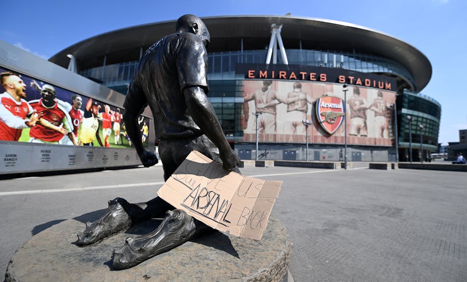Statue outside of Arsenal Emirates Stadiium with sign saying "Give us our Arsenal Back"