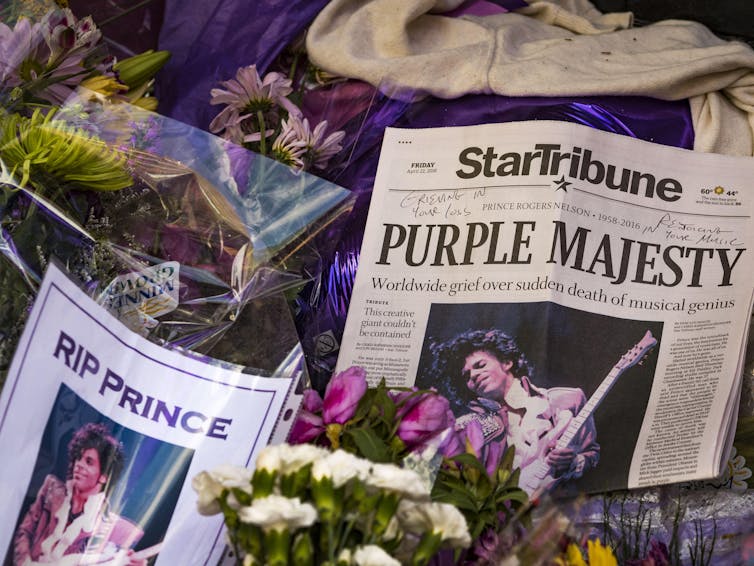 Memorial for the artist Prince with newspaper cuttings from the day of his death, flowers and a sign that says 'RIP Prince'
