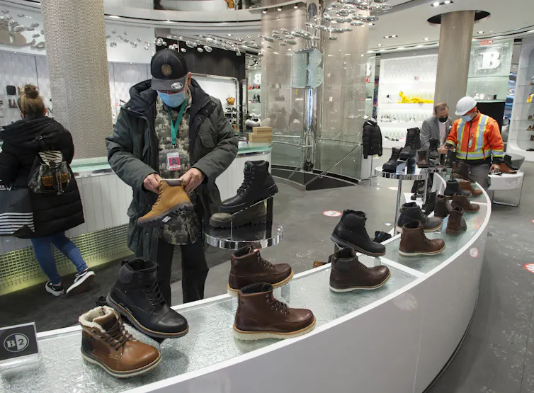 Customers in masks look at shoes in a shoe store.