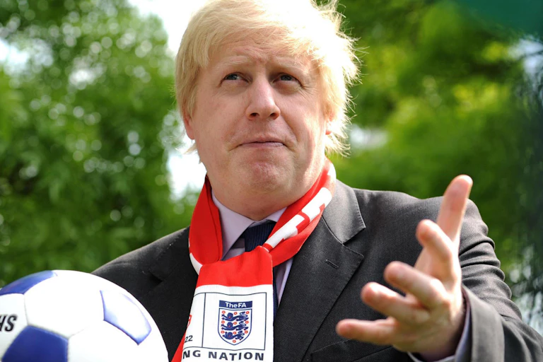 Boris Johnson holding a football wearing an England scarf