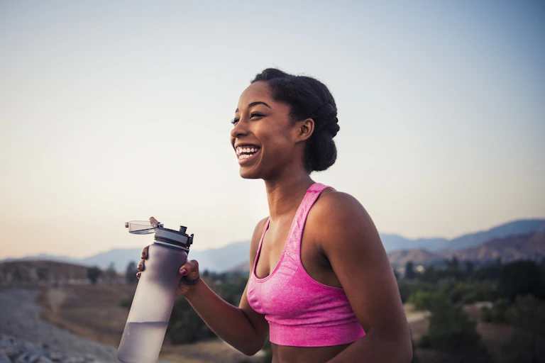 A woman outdoors holding a bottle of water.