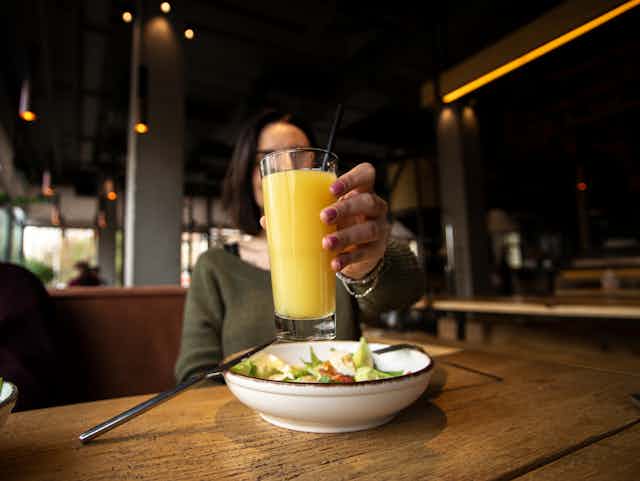 A woman holds up a glass of orange juice.