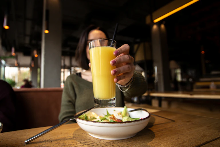 A woman holds up a glass of orange juice.