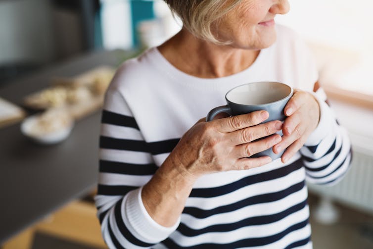 A woman in a striped jumper holds a mug.