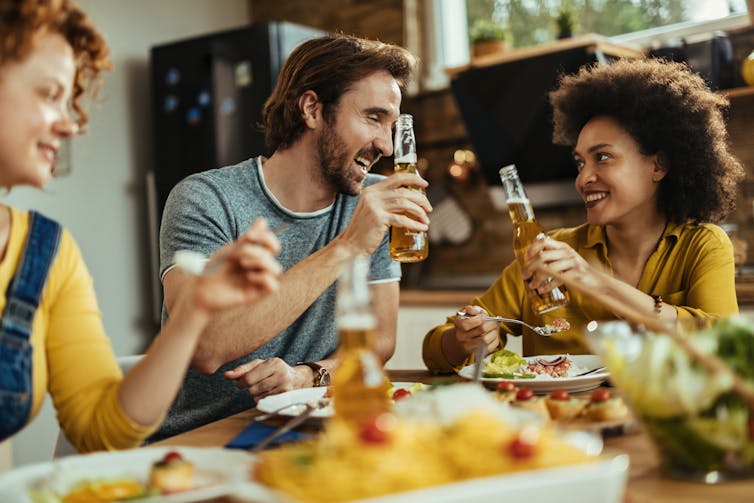 A group of people drinking beers with a meal.