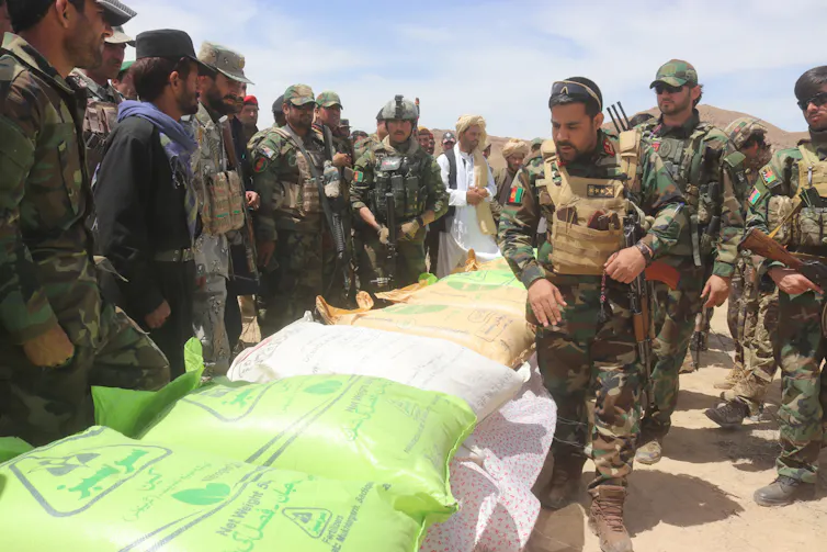 Afghani soldiers looking at bags of ammonium nitrate.