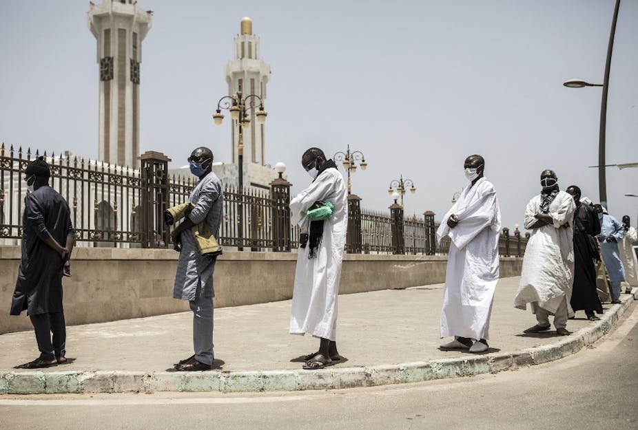 Des fidèles font la queue pour se laver les mains avant la prière du vendredi à la mosquée des Mourides, qui ouvre pour ses premières prières du vendredi après deux mois à Dakar, le 15 mai 2020.