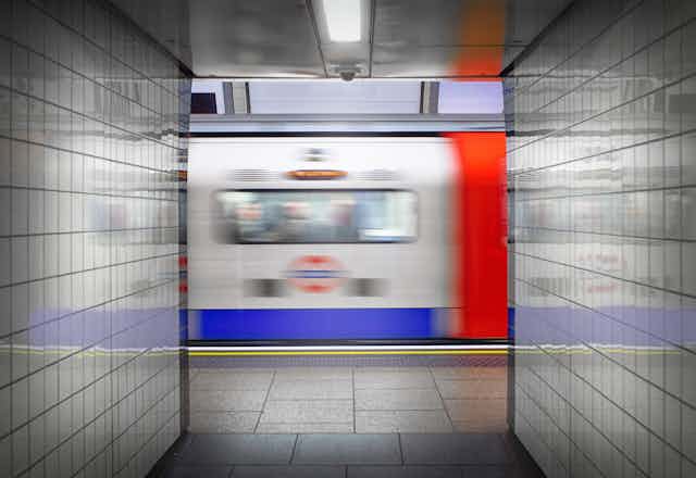 A tube train rushes past a tiled tunnel on the London Underground