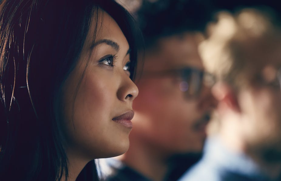 A young Asian American woman watches a presentation.