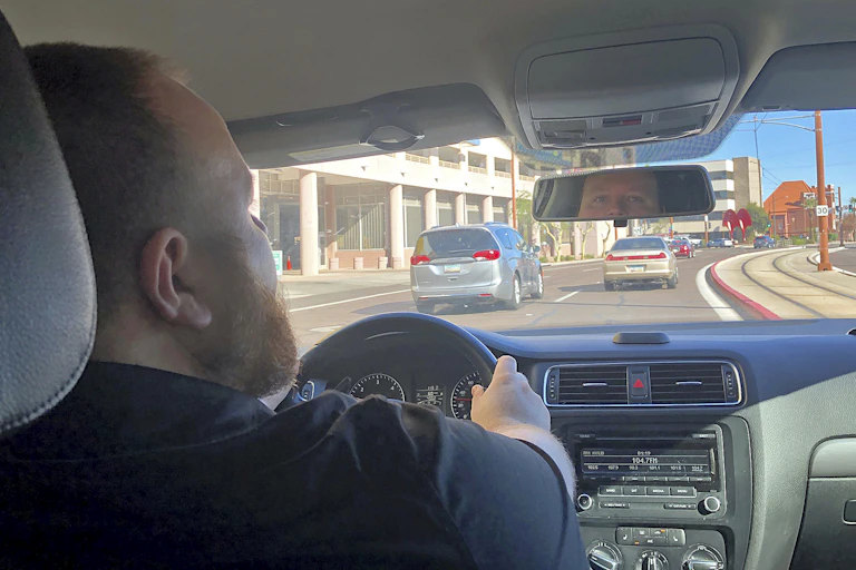 An Uber driver looks in the rear view mirror as he drives on a road near the Phoenix airport.