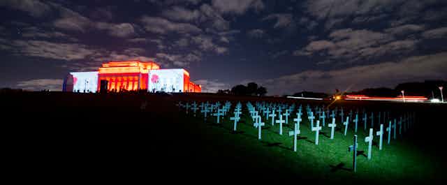 War Memorial Museum with poppies projected on walls and white crosses on front lawn