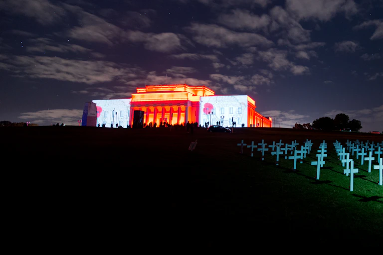 War Memorial Museum with poppies projected on walls and white crosses on front lawn
