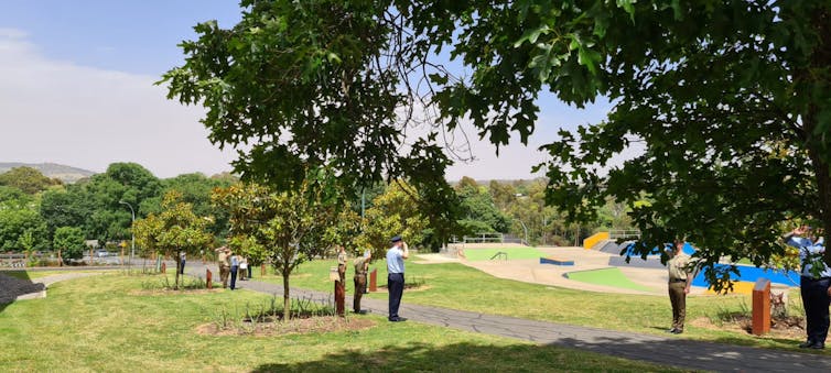 Soldiers salute near trees