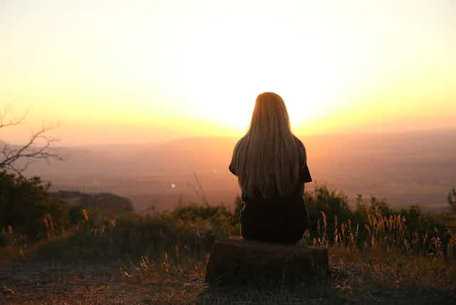 Woman sitting alone watching sunset.