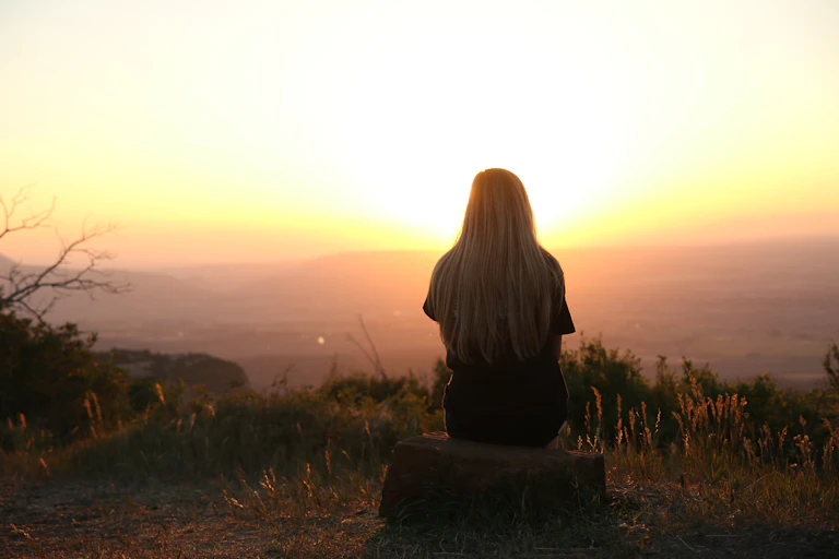 Woman sitting alone watching sunset.