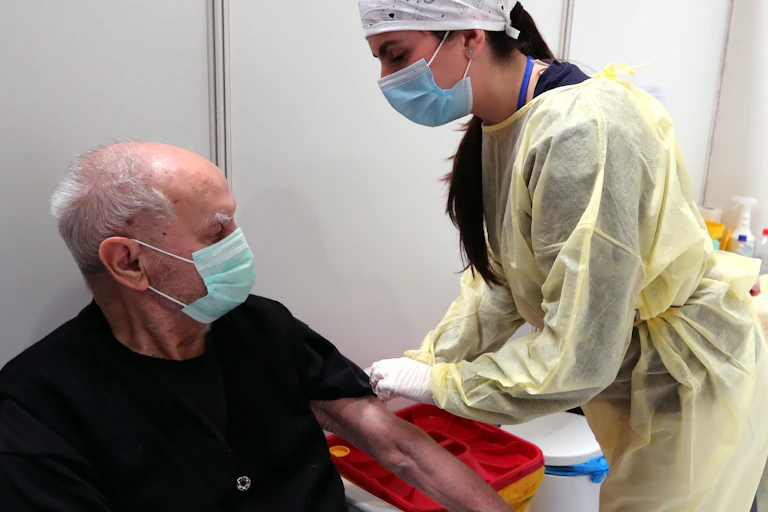 A nurse administering a dose of the AstraZeneca vaccine to a man