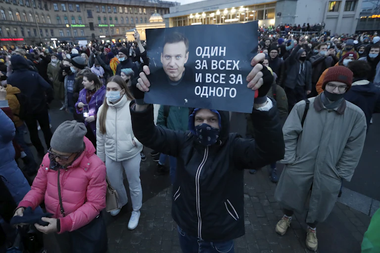 A protester in St Petersburg, Russia holds up a banner with a picture of dissident leader Alexei Navalny. In the background are thousands of other demonstrators.