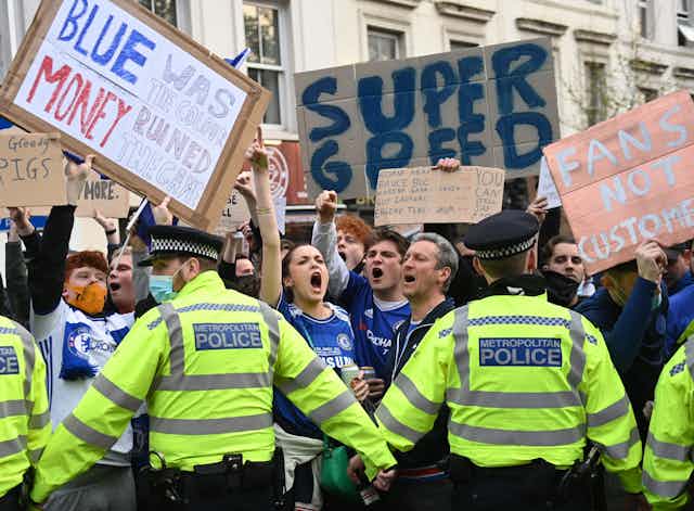 Protesting football fans held back by a line of police. 