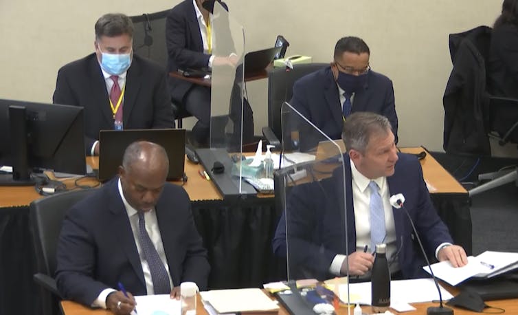 Two members of the prosecution team in the Chauvin case, sitting at their desk in the courtroom.