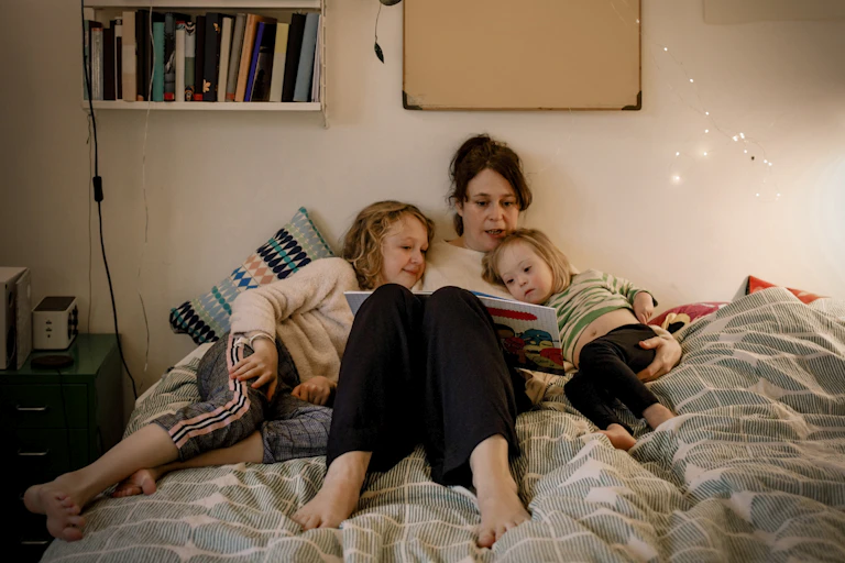 A woman reads to her children in bed