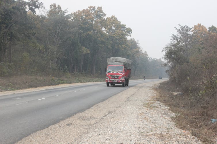 Bus on road with forests on either side.