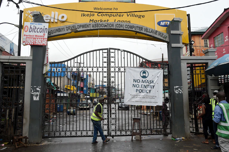 Men wearing reflective jackets standing at the main gate of Computer Village, Lagos.