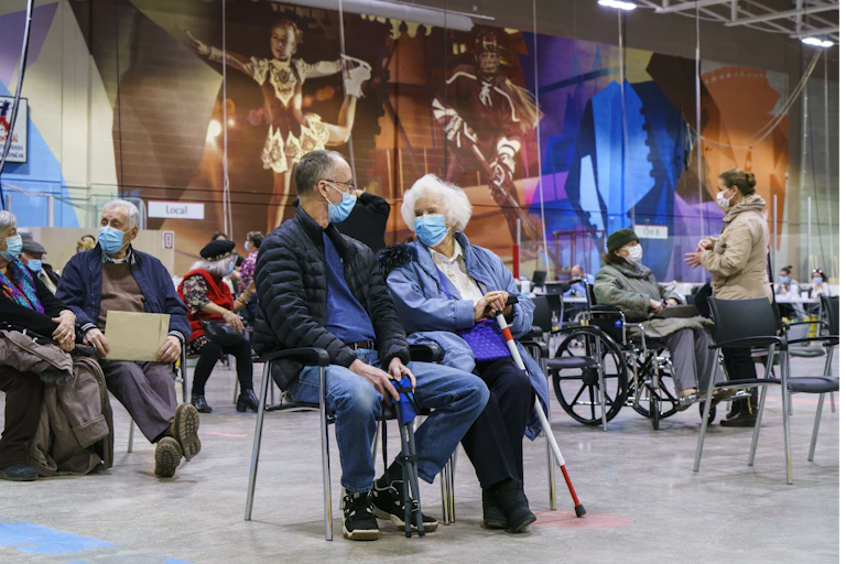 Man and woman sit wearing masks