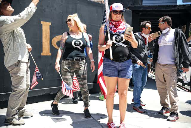 A group of protesters, including two women with QAnon emblems on their t-shirts, rallying against pandemic restrictions in California.