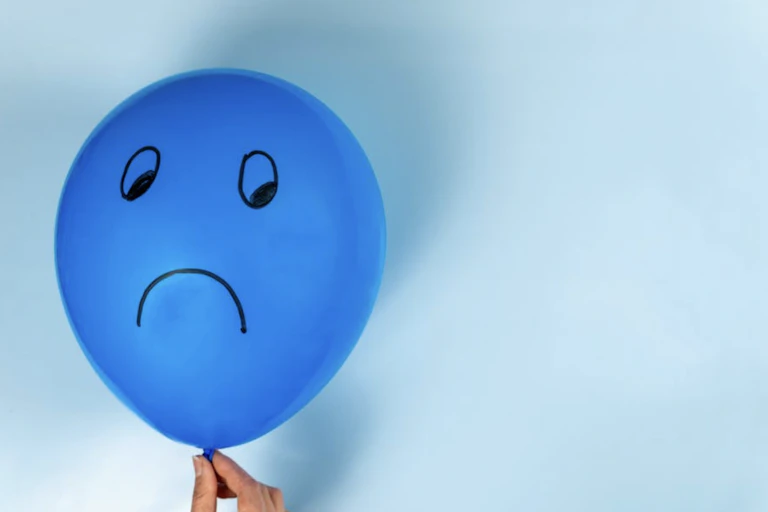 Blue balloon with a sad face on it