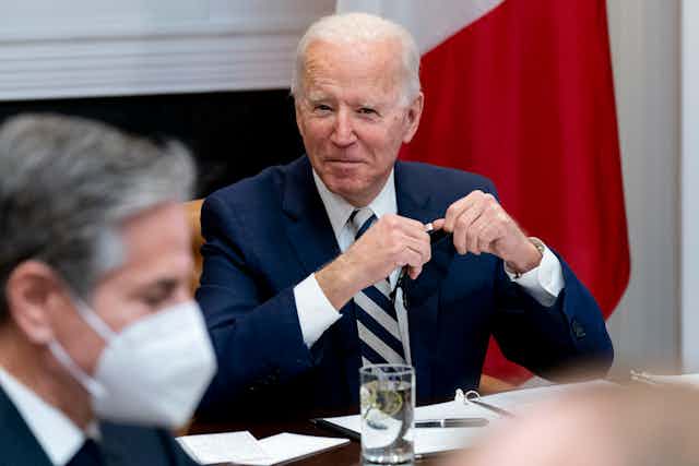 Biden smiles while Blinken is seen in the foreground wearing a mask.