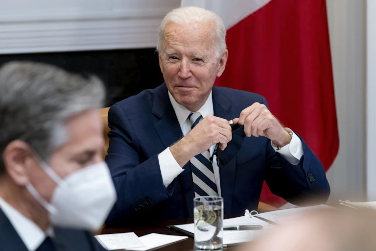 Biden smiles while Blinken is seen in the foreground wearing a mask.
