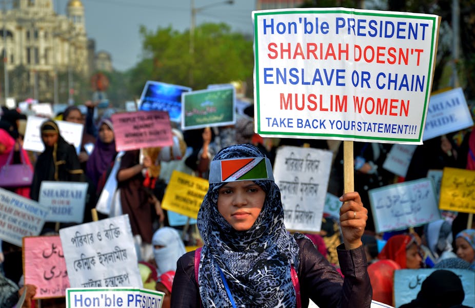Indian women holding placards saying, 'Sharia does not enslave or chain Muslim women,' during a protest in Kolkata, India.