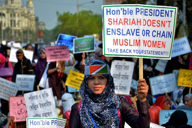 Indian women holding placards saying, 'Sharia does not enslave or chain Muslim women,' during a protest in Kolkata, India.