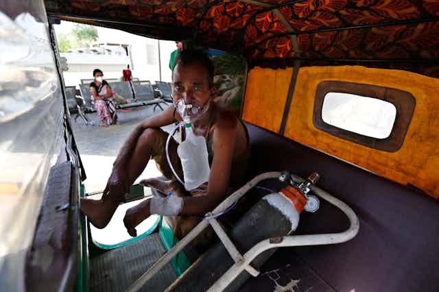 A COVID-19 patient in India receiving oxygen in a rickshaw while awaiting entry into a hospital